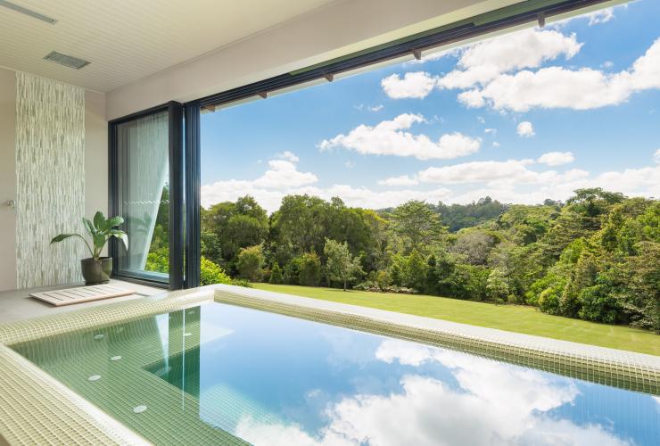 Open landscape windows look over the verdant rainforest from the Spicers Tamarind Hydrotherapy Pool in Noosa, Queensland © Spicers Retreats