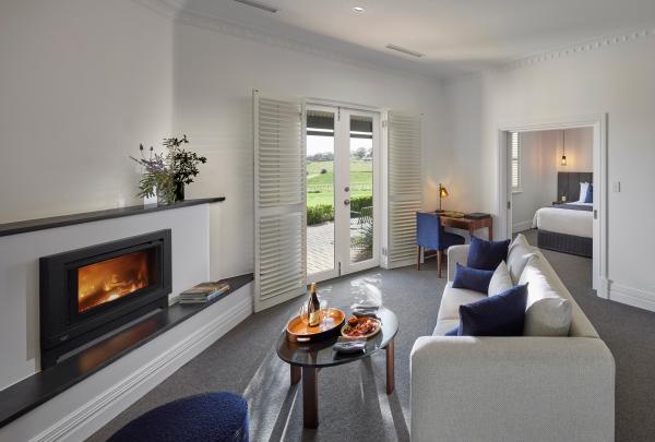 A glowing fireplace warms a stylish suite with plush seating and open doors leading out to vineyard views, operated by Baillie Lodges, at The Louise, Barossa Valley, South Australia. © George Apostolidis