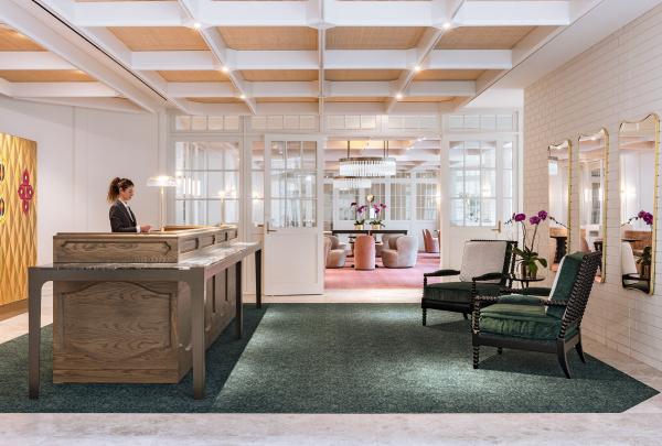 A receptionist stands at an elegant wooden counter in a refined lobby with green armchairs and coffered ceilings, operated by InterContinental, at Sorrento, Mornington Peninsula, Victoria. © InterContinental