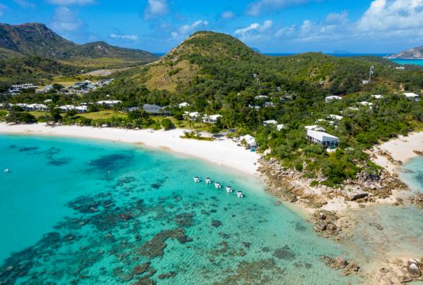 Aerial view of white sand beaches and turquoise reef waters fringed by lush green hills, Lizard Island, Queensland. © Lizard Island