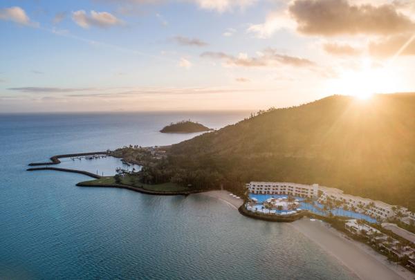 Golden morning light spills across lush hills and a calm bay, with the InterContinental Hayman Island Resort in the foreground, Hayman Island, Queensland. © The InterContinental Hayman Island