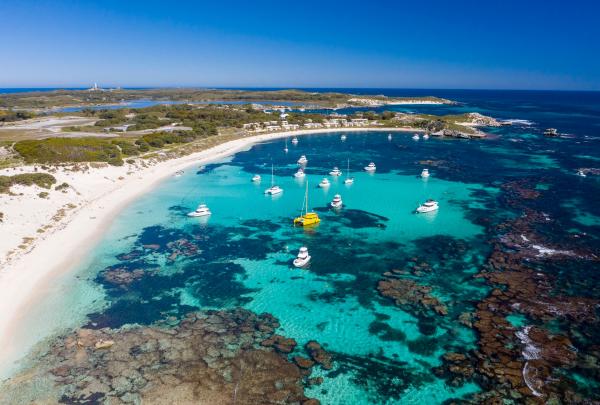 An aerial view reveals boats anchored in turquoise waters fringed by white sandy beaches and coral reefs, Rottnest Island, Western Australia. © Scott Slawinski