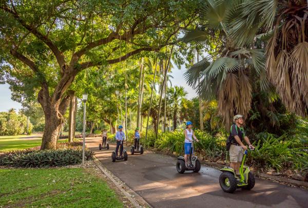 A guided group glides on Segways along a paved path beneath towering tropical palms and leafy shade trees in the George Brown Darwin Botanic Gardens, Darwin, Northern Territory. © Nick Pincott