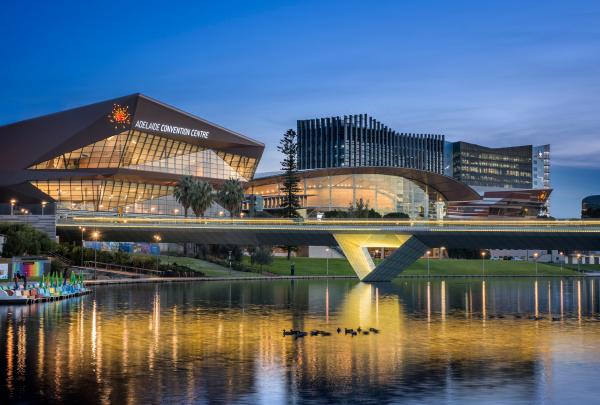 Striking contemporary architecture reflects softly off twilight waters beneath a glowing pedestrian footbridge at Adelaide Convention Centre, South Australia. © Adelaide Convention Centre