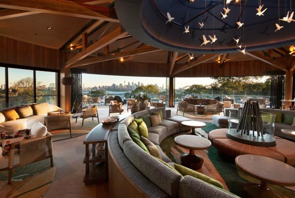 Circular lounge seating beneath bird-pendant lights fills a stylish open-air sanctuary with views of Sydney's skyline, Wildlife Retreat at Taronga, Sydney, New South Wales. © Taronga Zoo