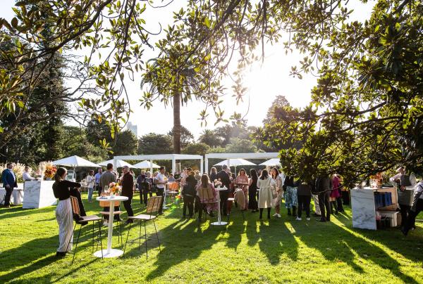 Guests socialise at an outdoor garden event on sunny lawns surrounded by leafy trees with Curtis Stone Events, Melbourne, Victoria. ©  Curtis Stone Events