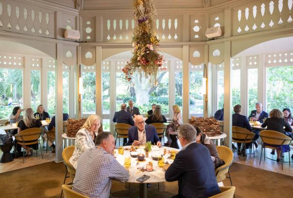 Diners enjoy a meal in an elegant, sunlit dining room surrounded by lush gardens at Restaurant Botanic inside the Adelaide Botanic Gardens in Adelaide, South Australia © Tourism Australia