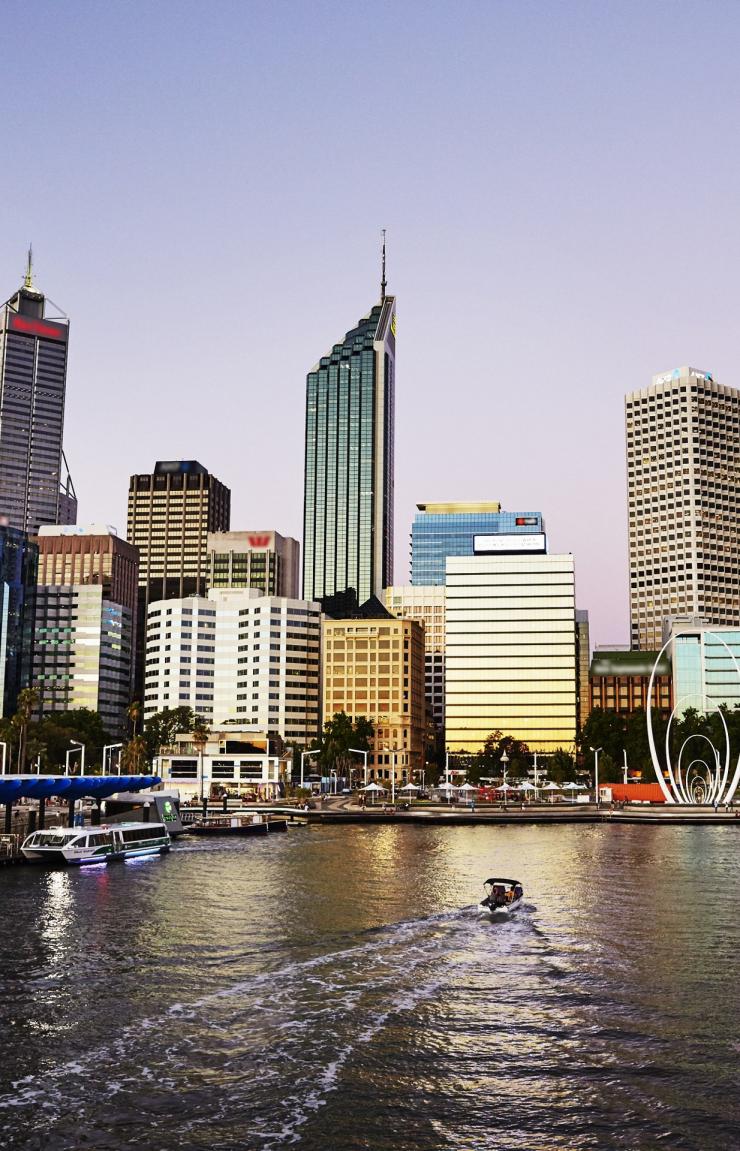 A boat creates a wake across the dark waters of Elizabeth Quay as dusk falls over the glowing Perth city skyline, Western Australia. © Dianna Snape