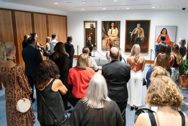 Visitors gather in a gallery room as a guide presents large portraits from the Parliament House Art Collection, Australian Parliament House, Canberra, Australian Capital Territory. © Australian Parliament House