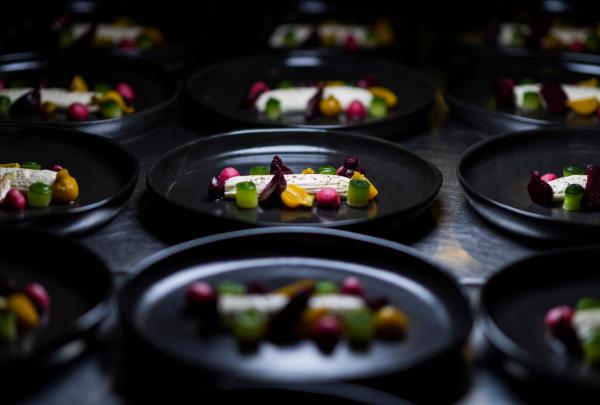 Multiple dark plates lined up in a row display a fine dining dish featuring vibrant beetroots, gel drops, and central whipped cheese at National Convention Centre Canberra, Canberra, Australian Capital Territory © National Convention Centre Canberra