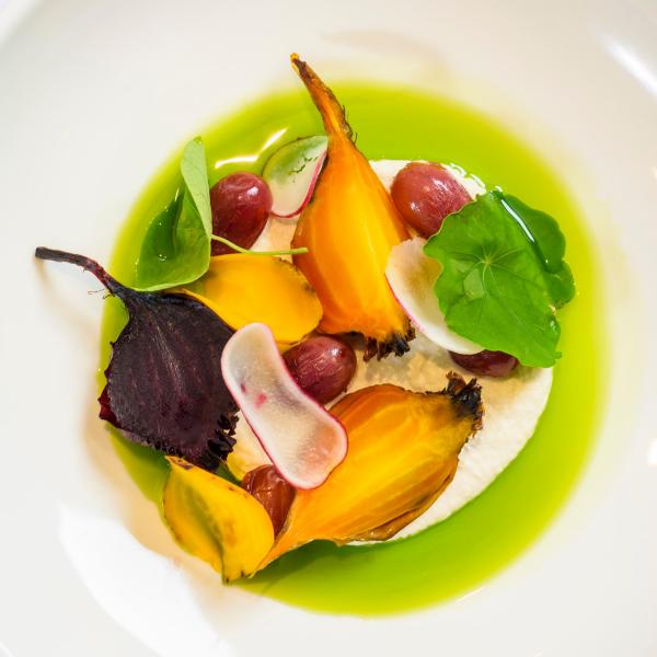 A colourful dish of roasted golden and red beets, radishes, and fresh greens sits atop cream and a bright herb oil at Adelaide Convention Centre, Adelaide, South Australia. © Adelaide Convention Centre