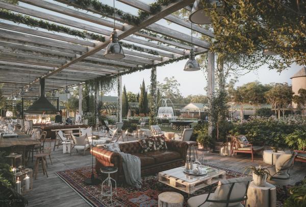 A stylish outdoor terrace with a wooden pergola, leather sofa, and open fireplace amidst lush gardens, designed for Six Senses, Melbourne, Victoria. © Klickx