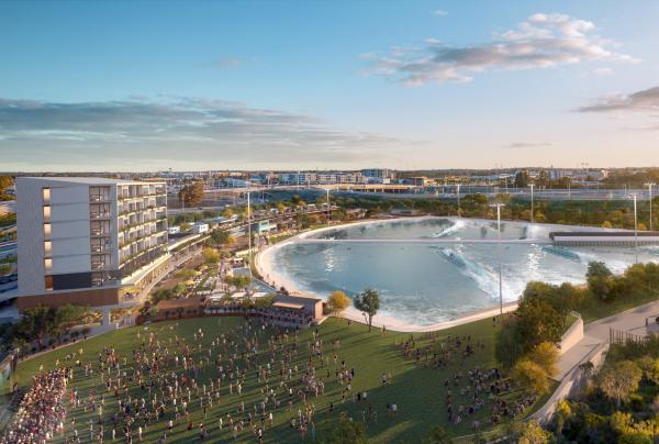 Aerial view of a sprawling wave lagoon, grassy event lawn, and modern amenities building under clear skies, designed for Aventuur at Perth Surf Park, Perth, Western Australia. © Aventuur