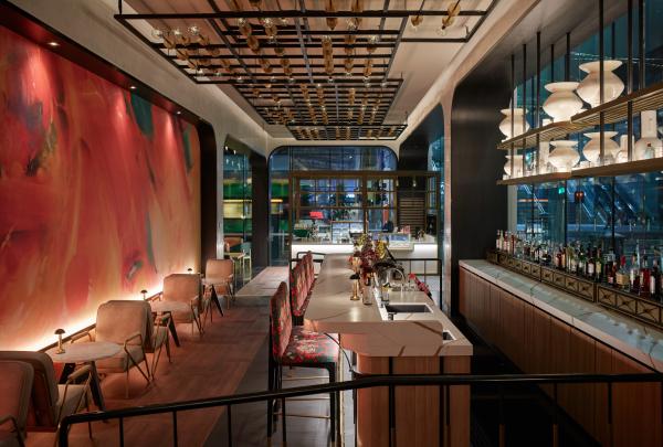 A chic cocktail bar showcases patterned high stools, warm ambient lighting, and a vibrant backlit abstract wall panel, Mövenpick Hotel, Melbourne, Victoria. © Kristoffer Paulsen