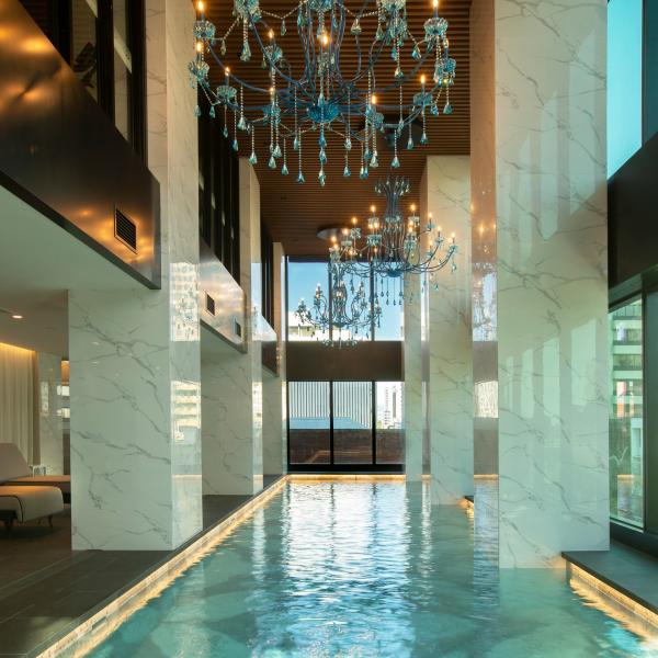 Ornate blue chandeliers illuminate a long indoor lap pool framed by grand marble pillars, Sofitel Adelaide, Adelaide, South Australia. © Sofitel Adelaide