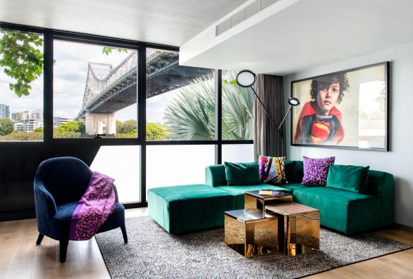 A vibrant green velvet sofa and metallic nesting tables fill a modern suite with floor-to-ceiling windows framing the Story Bridge, Crystalbrook Vincent, Brisbane, Queensland. © Crystalbrook Vincent