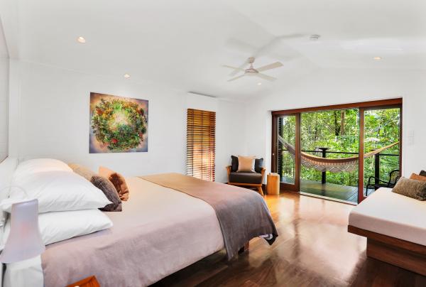 A spacious modern bedroom opens onto a private balcony with a woven hammock nestled amidst dense tropical foliage, Silky Oaks Lodge Garden Retreat, Daintree Rainforest, Tropical North Queensland. © Silky Oaks Lodge