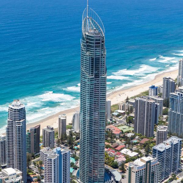 An aerial view of the Q1 skyscraper standing tall over surrounding high-rises and the turquoise ocean along the coastline at SkyPoint, Gold Coast, Queensland. © Rix Ryan