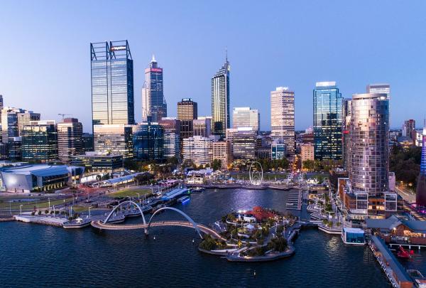 A twilight aerial view reveals illuminated city skyscrapers towering above Elizabeth Quay and the Swan River, Perth, Western Australia. © Tourism Australia