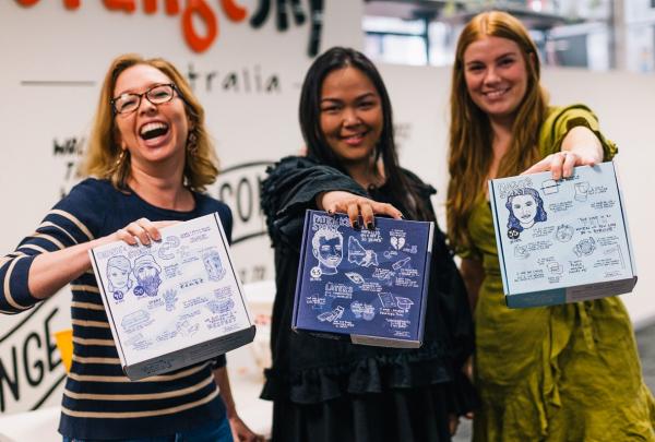 Group of women holding up packaged boxes of homeless essentials for a team building exercise © Corporate Challenge Events