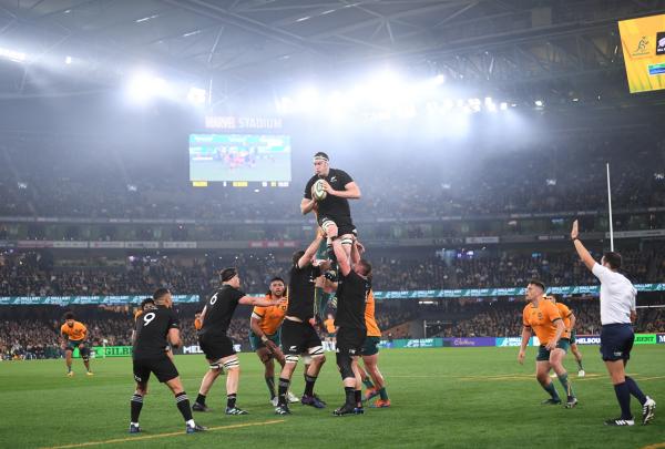 Rugby players leap during a high lineout contest under bright floodlights at a packed Bledisloe Cup match at Marvel Stadium in Melbourne, Victoria. © Rugby Australia