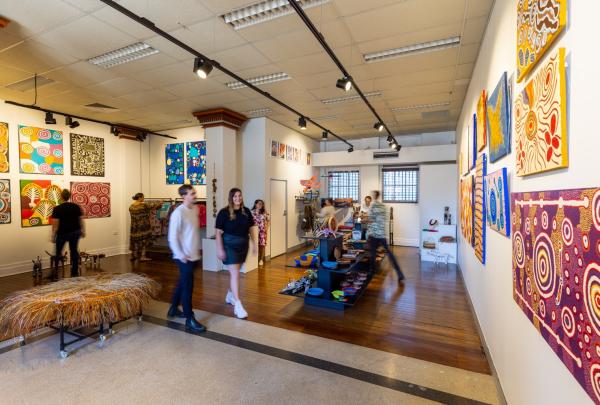 Visitors browse colourful Indigenous artworks and cultural items displayed in a modern gallery space with Aboriginal Art Co, Brisbane, Queensland. © Aboriginal Art Co
