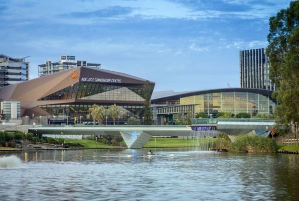 Modern metallic glass buildings overlook a river and pedestrian bridge under dusk skies at Adelaide Convention Centre, Adelaide, South Australia.© Adelaide Convention Centre