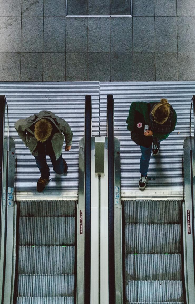 An aerial view of commuters riding escalators and checking their smartphones on tiled station concourses, Sydney, New South Wales.© Shane Rounce & Australia Unlimited
