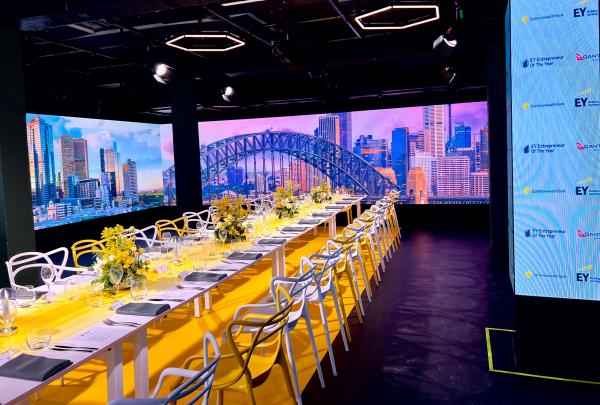 Long banquet table set for a event, framed by immersive LED screens showing cityscapes, hosted by LIGHT Adelaide, Adelaide, South Australia. © LIGHT Adelaide