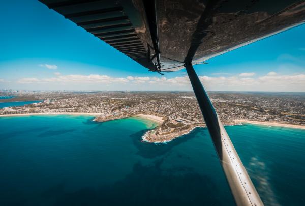 An aerial wing-view highlights pristine turquoise bays, sandy beaches, and coastal suburbs during a scenic flight over Sydney Harbour, New South Wales, operated by Sydney Seaplanes. © Sydney Seaplanes