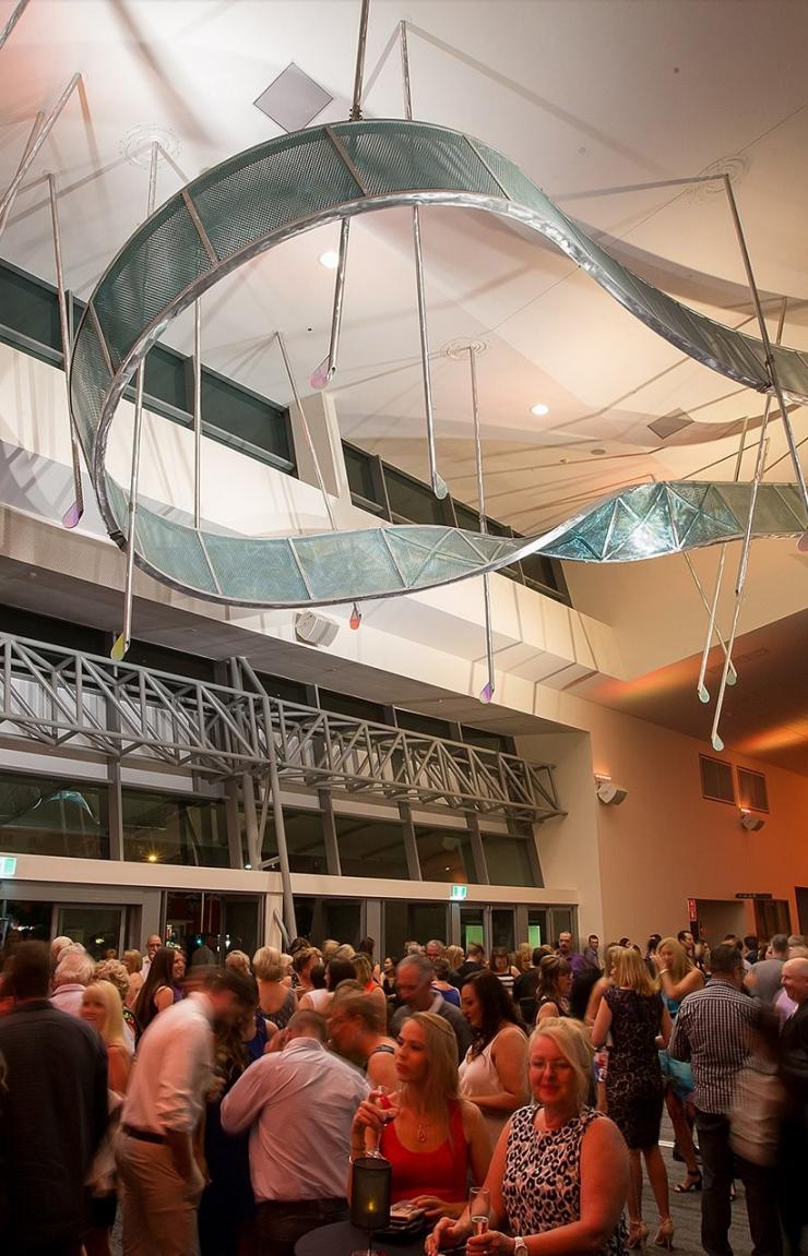 Guests gather in a modern foyer beneath a suspended curved ceiling art piece at Gold Coast Convention and Exhibition Centre, Gold Coast, Queensland. © Gold Coast Convention and Exhibition Centre