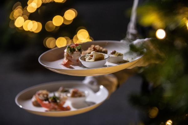 A server carries two white plates of gourmet canapés past warm bokeh lights during an event at the Gold Coast Convention and Exhibition Centre, Gold Coast, Queensland. © Gold Coast Convention and Exhibition Centre