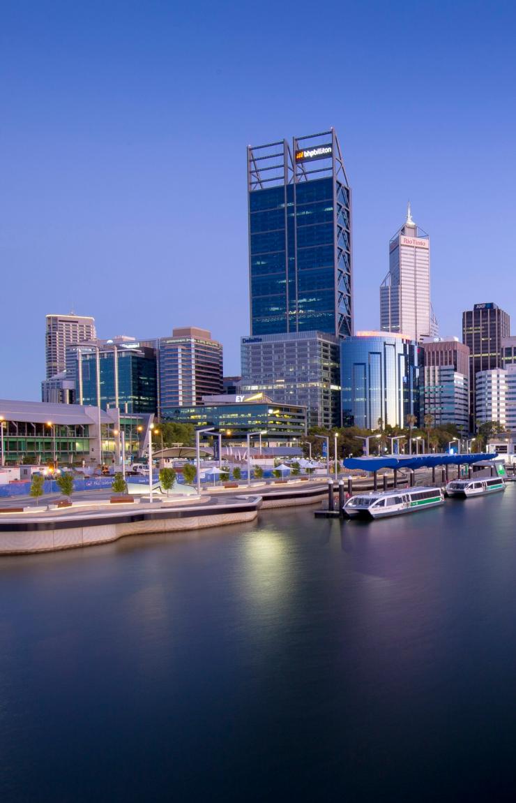 The modern, low-rise Perth Convention and Exhibition Centre sits beside the tranquil waters of Elizabeth Quay as dusk settles over the city skyline in Perth, Western Australia. © The Scene Team