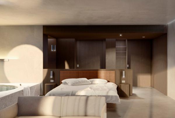 A luxurious hotel suite interior at Levantine Hill Estate, Yarra Valley, Victoria, featuring a stylish bed, neutral tones, dark timber accents, and soft sunlight streaming across concrete walls. © Levantine Hill Estate