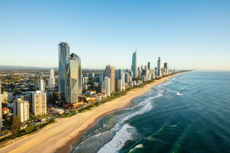 An aerial view over Surfers Paradise Beach captures a lively scene under bright sunshine, Gold Coast, Queensland © Tourism Australia