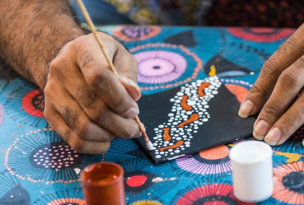 Indigenous artist, Brian "Binna" Swindley, showing guests painting techniques during an Aboriginal Art Class at the Janbal Gallery, Down Under Tours, Mossman Gorge, Queensland © Tourism and Events Queensland