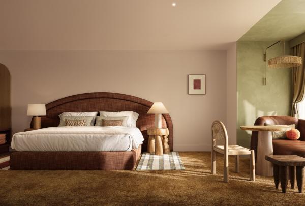 A stylish hotel bedroom at Hyde Perth in Western Australia features a large bed with a curved terracotta headboard, warm ochre carpet, a brown leather daybed, a unique wooden table, and a soft sage-green feature wall. © Hyde Perth