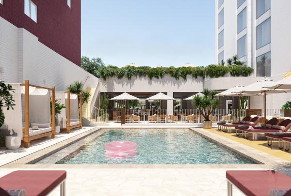 The sun-drenched outdoor pool deck at Hyde Perth in Western Australia features a sparkling swimming pool with a pink inflatable ring, surrounded by maroon sun loungers, chic white umbrellas, and wooden cabanas under a clear blue sky. © Hyde Perth