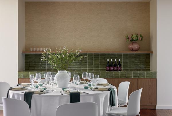 A chic round banquet table setting at Hyde Perth, Western Australia, features a crisp white tablecloth, dark green napkins, premium wine glassware, and a central floral vase against a glossy green-tiled wall with timber joinery. © Jenna French