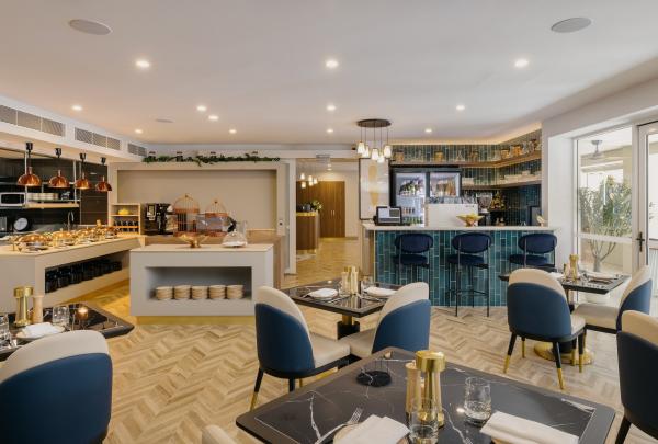 The modern, stylish restaurant at voco Darwin Suites in Darwin, Northern Territory, features elegant dark blue and cream chairs, marble-look tables, herringbone timber floors, a buffet station, and a blue-tiled bar area. © voco Darwin Suites