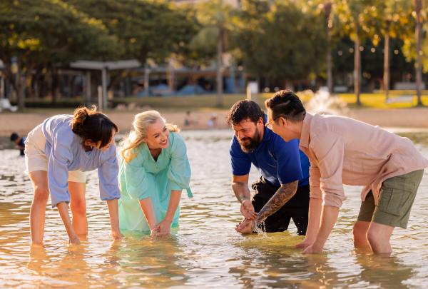 Four people standing in the water partaking in a cultural ceremony © Jason Ierace