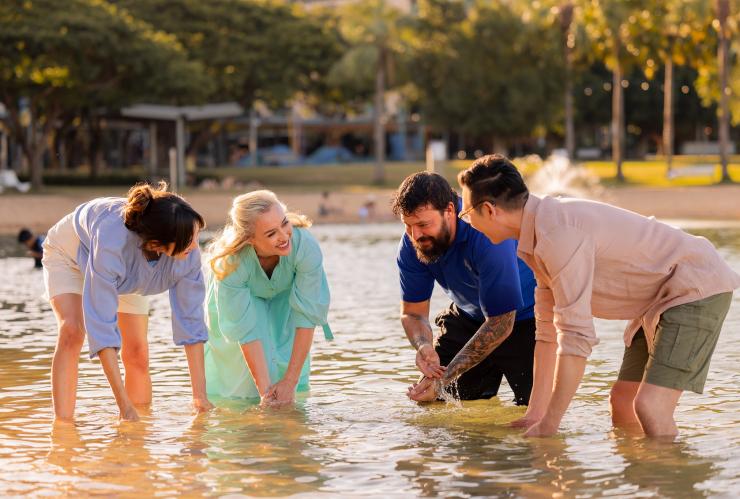 Four people standing in the water partaking in a cultural ceremony © Jason Ierace