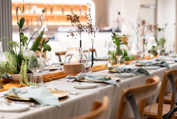 A close up of a long dining table set with wine glasses, linens and native florals. © Avani Mooloolaba Beach Hotel