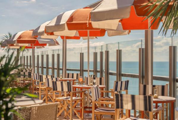 A rooftop terrace with deck chairs, tables and umbrellas positioned next to the railing so as to enjoy the ocean view. © Rhiannon Taylor / Avani Mooloolaba Beach Hotel