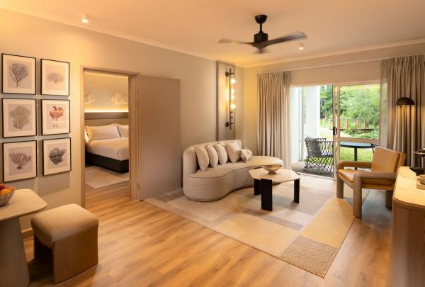 A tropical hotel suite with a sliding door, accessing the lush garden, a sitting room and a bedroom. © Hilton Palm Cove Cairns Resort & Spa