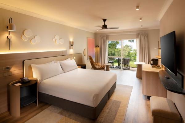 A modern hotel room with comfortable amenities and glass door leading onto the garden outside. © Hilton Palm Cove Cairns Resort & Spa