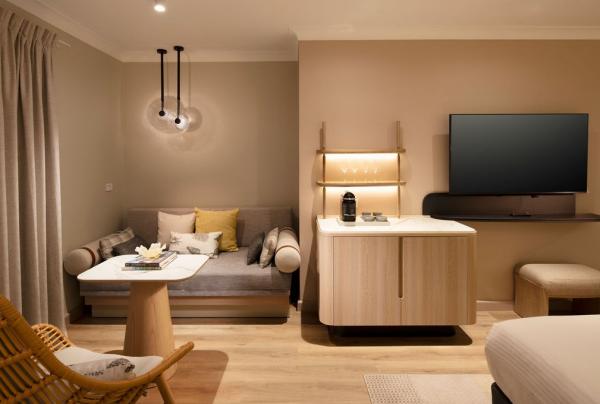A modern hotel room with a corner nook, bar, small table, television and bed. © Hilton Palm Cove Cairns Resort & Spa