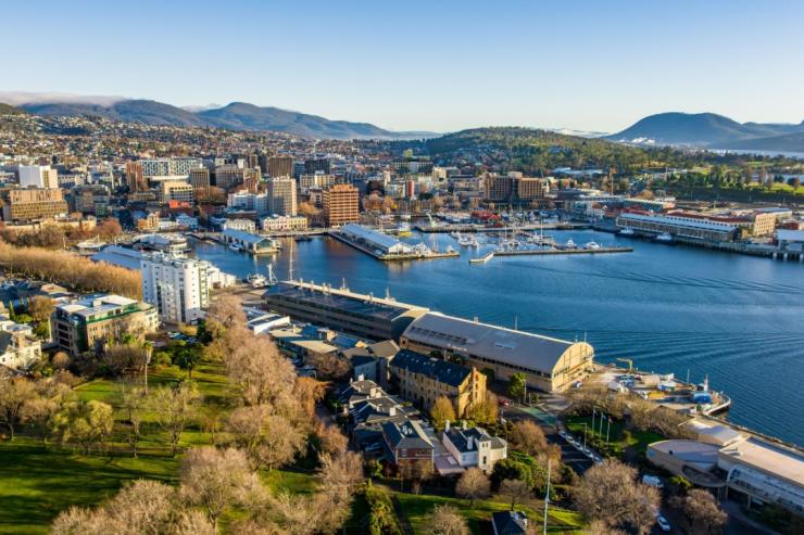 An aerial view of Hobart Harbour reveals the Institute for Marine and Antarctic Studies alongside the CSIRO, sitting prominently by the water. In the background, Salamanca, Elizabeth Street Pier, and Constitution Dock bustle with activity. © Tourism Australia