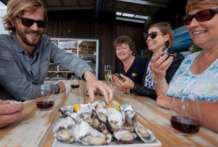A group tucks into freshly shucked oysters on the Bruny Island Traveller Tour, Tasmania  © Hype TV and Aerial Vision Australia