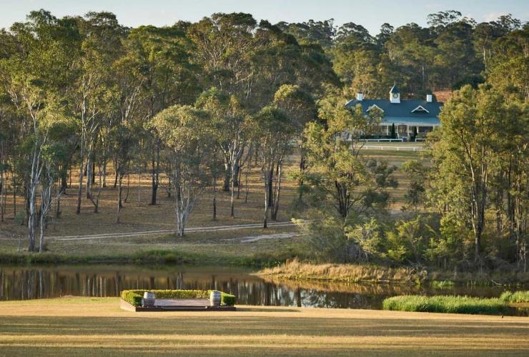 A landscape view of the Cricketer’s Pavillion amongst trees with a lake in the foreground at Wandin Valley Estate, Hunter Valley, New South Wales © Doltone House